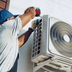 Repairman in uniform installing the outside unit of air conditioner close up